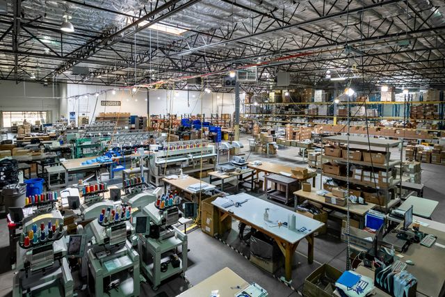 Overhead view of Silverscreen's embroidery floor in Reno, with rows of multi-head embroidery machines, work tables and shelving