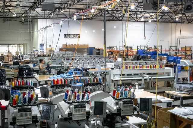 Embroidery department with multi-head embroidery machines loaded with colorful thread cones