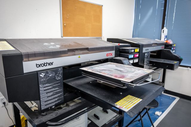 Brother GTX direct-to-garment printer with a shirt on its platen, with a second GTX printer beside it