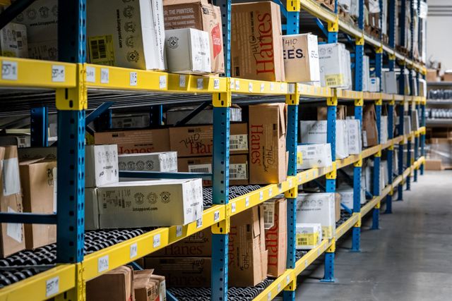 Warehouse racks lined with boxes of blank garments from Hanes and other brands