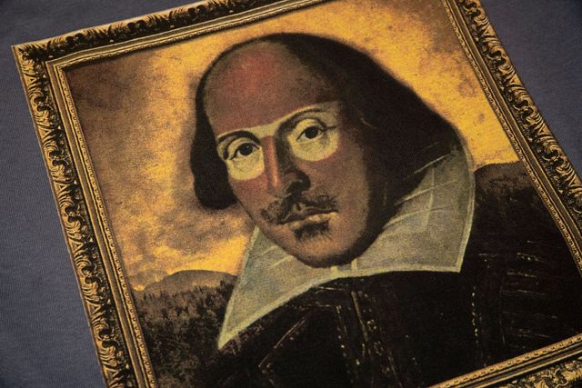 Simulated process print of a framed Shakespeare portrait on a navy shirt