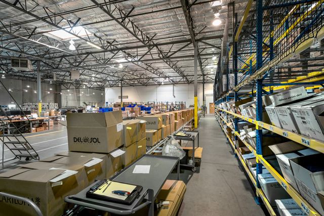 Silverscreen warehouse with stacked boxes, carts and tall shelving full of orders